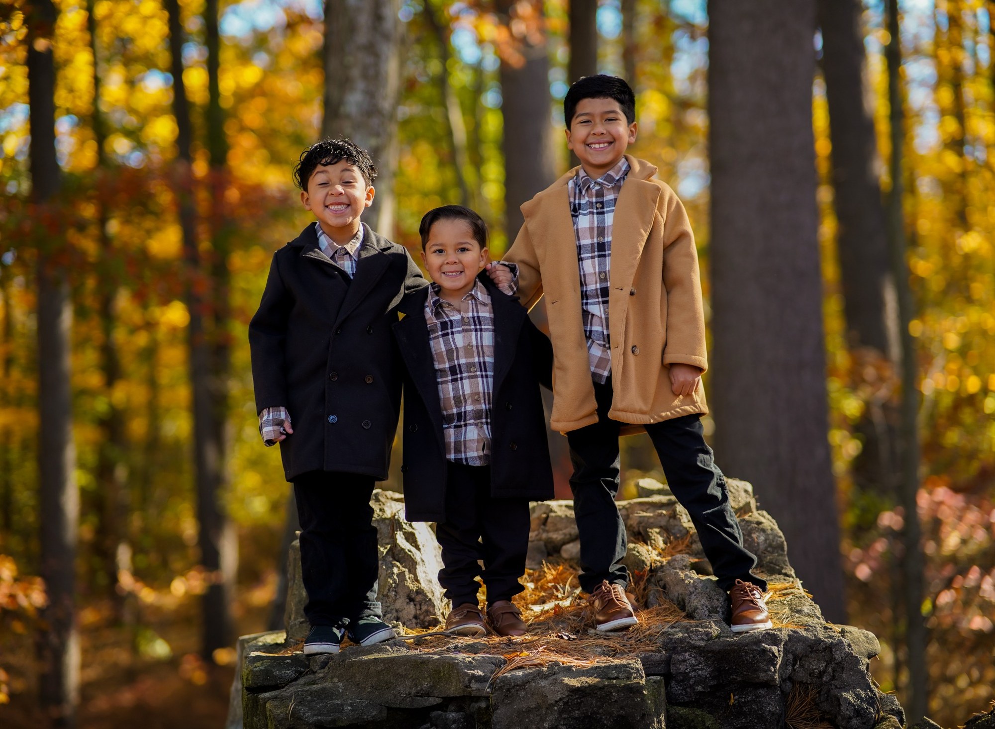 Tres hermanos posando juntos en un bosque de otoño