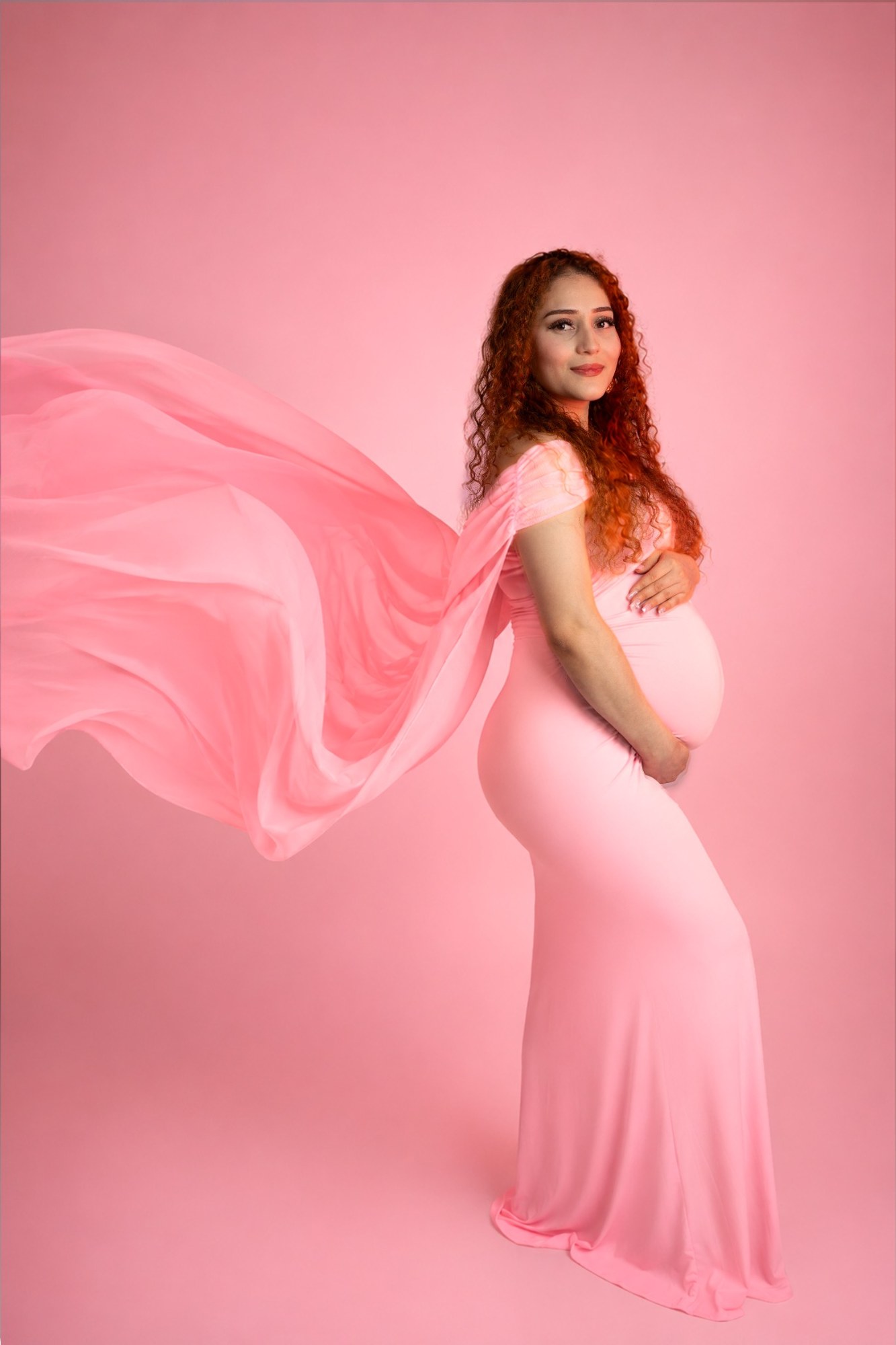 Retrato de maternidad con vestido rosa y tela en movimiento